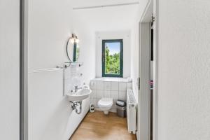 a white bathroom with a toilet and a window at Jenapartments Pension - Studios mit Küche in Jena