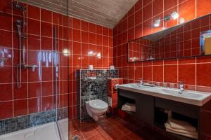 a red tiled bathroom with a toilet and a sink at Pensiunea Warthe Bed & Breakfast in Braşov