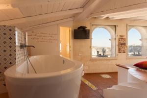 a large white tub in a bathroom with two windows at Casa Diva in Matera