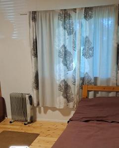 a bedroom with a bed and a curtain and a radiator at Järvitalo in Soini