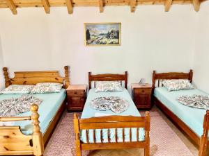 two beds in a room with two chairs and two tables at Bujtina Te Grima in Theth