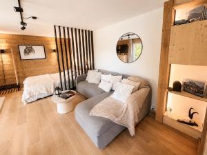a living room with a couch and a mirror at L'Aiglon- Piscine Naturelle Privatisable in Salvan
