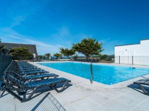 a swimming pool with blue lounge chairs next to it at Sud Ocean L N94 2P4 in Guidel