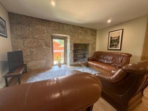 a living room with leather furniture and a stone wall at Villa Lijó Suites in Rio Caldo