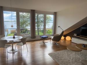 a living room with a table and chairs and windows at Seepanorama in Groß Wittensee