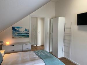 a white bedroom with a bed and a tv at Seepanorama in Groß Wittensee +16 photos