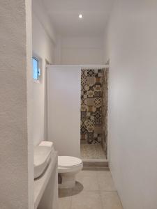 a white bathroom with a toilet and a shower at Depas las Palmas in Zihuatanejo