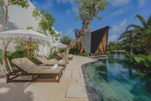 a resort pool with lounge chairs and a house at Nuju Uluwatu - Adults Only in Uluwatu