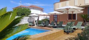 a pool with chairs and umbrellas next to a house at Bed & Breakfast La Villetta in Botricello