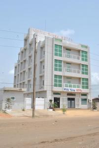 a large white building with green windows at White Horse Hotel Cotonou in Agblangandan