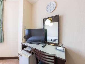 a desk with a computer and a clock on a wall at Tabist Hotel New Osamura Sabae Inter in Fukui