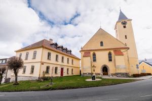 a church with a clock tower next to a street at Penzion Sborovna in Zbraslavice