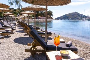 a row of lounge chairs and umbrellas on a beach at Alidian bay Suites Leros in Alinda