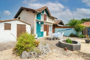 a blue and white house with a table and chairs at Escapade Landaise, Piscine in Capbreton