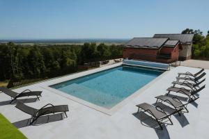 a swimming pool with chairs and a building at Marmor Collis by Winery Glavica in Gornja Gračenica