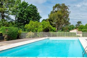 a swimming pool in front of a fence at Escapade Landaise, Piscine in Capbreton