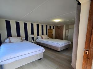 two beds in a room with striped walls at NiNETEEN28 Guesthouse in Pietermaritzburg