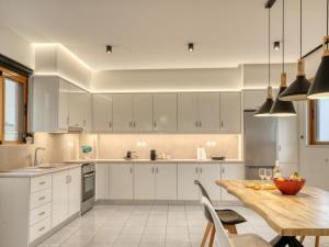 a kitchen with white cabinets and a wooden table at Azure Seaside Living in Kardamaina