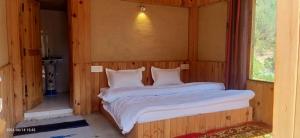 a bedroom with a bed in a wooden room at Shikhar cottage in Jibhi +6 photos
