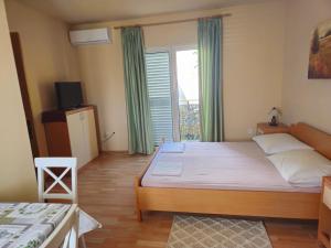 a bedroom with a bed and a television and a window at Apartmani Danja in Kaštela