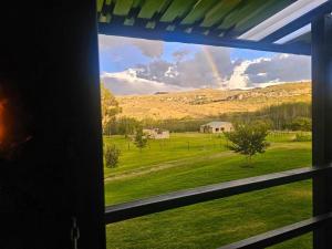 a view from a window of a field with a rainbow at Clarossouw in Clarens +3 photos