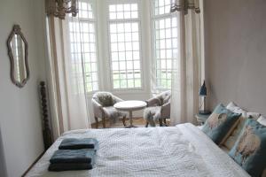 a bedroom with a bed and a table and windows at Le Relais du Doubs en Bourgogne in Ciel