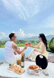 a man and woman sitting on a table with glasses of wine at Mây Villa HA in Yên Bài