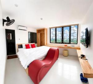 a bedroom with a large bed and a red chair at Habibi Hotel in Sóc Sơn