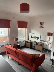 a living room with a red couch and a flat screen tv at 1 Bed Apartment Sleeps 3, Ferryhill Near Durham & WiFi in Ferryhill +9 photos
