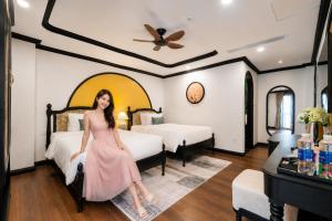 a woman sitting on a bed in a hotel room at Yzistel Hoi An in Hoi An