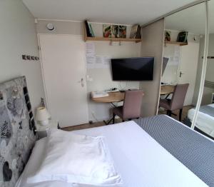 a bedroom with a bed and a desk and a television at Les Lavandins,Chambre climatisé, à 300 Tram L5, PARKING et WIFI gratuit in Montpellier