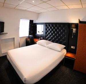 a bedroom with a large white bed with a black headboard at Budget Hotel Le Beau Rivage in Middelburg