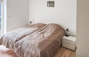 a white bedroom with a bed and a night stand at 2 Bedroom Nice Apartment In Samsø in Ballen