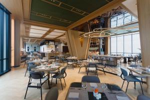 a restaurant with tables and chairs and windows at Harris Hotel & Convention Serpong in Tangerang