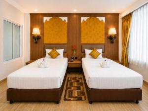 two beds in a hotel room with white sheets at Aiyara Palace in North Pattaya