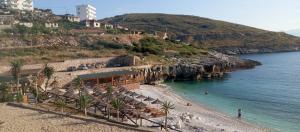 a beach with umbrellas and chairs on the shore at Apartments Polonia Saranda in Sarandë