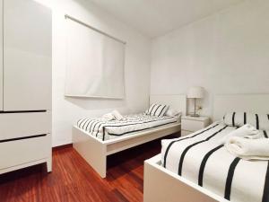 two beds in a room with white walls and wood floors at Apt 2 hab Camprodon, chimenea, terraza, céntrico in Camprodon