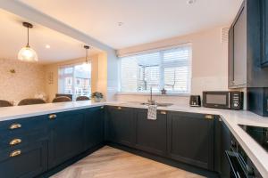 a kitchen with dark green cabinets and a microwave at Marsh House - Modern Apartment With Hot Tub in Whitstable