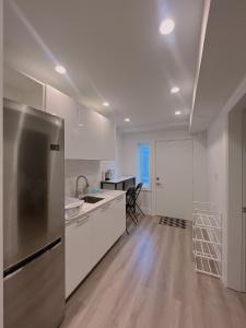 a kitchen with white cabinets and a stainless steel refrigerator at Claire House in Vancouver