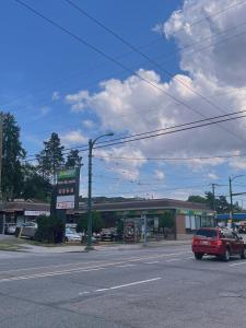 a red car driving down a street with a gas station at Claire House in Vancouver