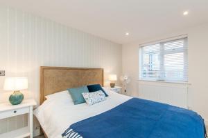 a bedroom with a large bed with a blue blanket at Marsh House - Modern Apartment With Hot Tub in Whitstable +8 photos