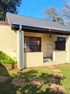 a small white house with a black roof at The Museum Cottage in Sabie