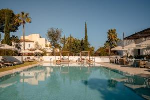 a large swimming pool with chairs and umbrellas at Kimpton Aysla Mallorca by IHG in Santa Ponsa