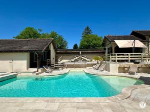 a swimming pool with two chairs and a house at Gîte des Pruniers in Saint-Germain-le-Rocheux
