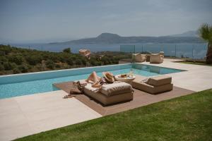 a pool with couches and chairs next to at Villa Niolos II in Stérnai +49 photos