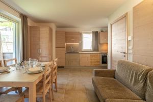 a kitchen and dining room with a table and a couch at Molveno Garden Suite in Molveno