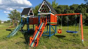 a playground with a slide and a play house at Atpūtas mājas Leiksnīte in Vaikulāni