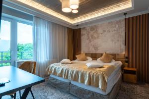 a bedroom with a bed and a desk and a window at Pensiunea Warthe Bed & Breakfast in Braşov