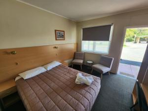 a bedroom with a bed and two chairs and a window at Murrurundi Motel - CITY CENTRE in Murrurundi