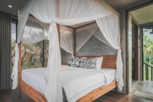a bedroom with a canopy bed with white drapes at Mangroove Bay Boutique Hostel in Banyuwedang +91 photos